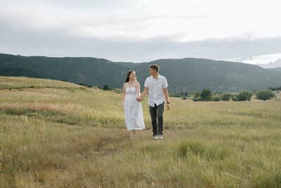 bride and groom snuggle in a field at sunset