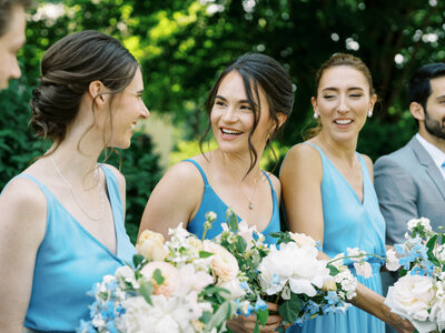Three bridesmaids in blue dresses smile at one another in Charlottesville, VA Bridesmaids Makeup