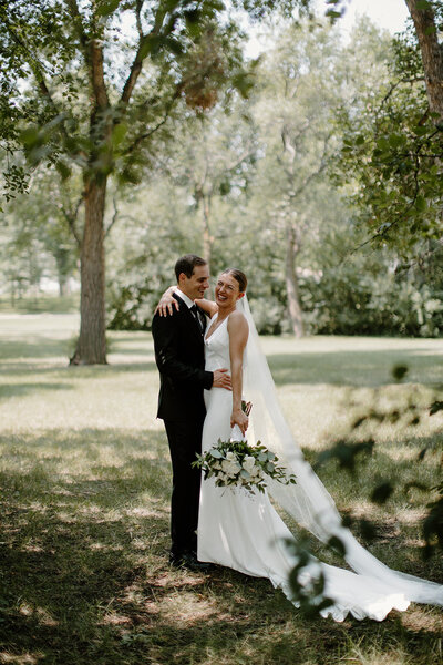 a bride and groom holding each other and laughing