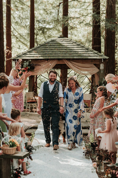 Newly weds celebrating with confetti after their wedding in the woods