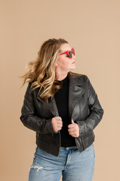 a blonde woman wearing heart shaped glasses tosses her hair side to side