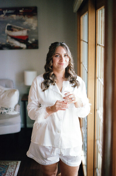 Bride standing by window in white bathroom
