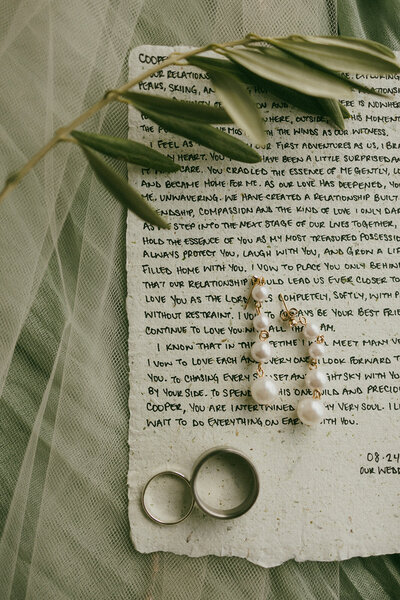 detail shot pearls , vows and rings on table