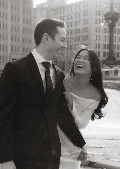 Black and white photo of a couple laughing together during their downtown Indianapolis engagement session near Bottleworks Hotel and Monument Circle, photographed by Rainstorm Photo & Video with a timeless, cinematic feel.