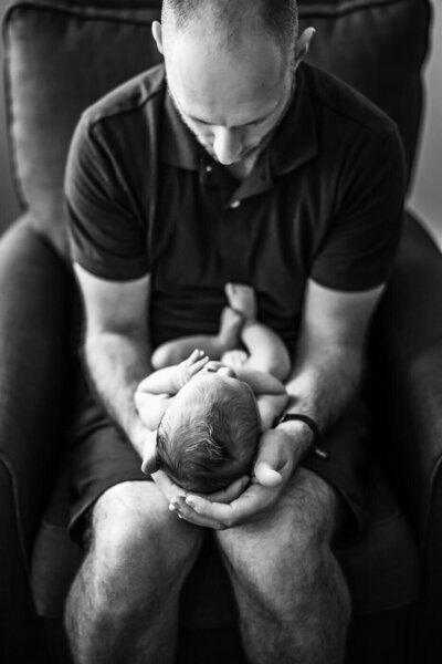 A tiny baby lies in his crib on his tummy wearing his newborn size diaper.