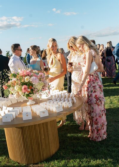 Guests admire a luxury escort card display designed by Courtney Elizabeth Events, featuring elegant florals, candles, and modern wedding decor.