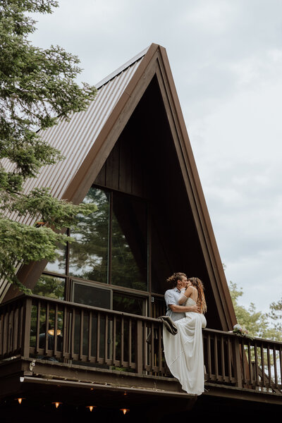 bride and groom on the deck of an a-frame cabin
