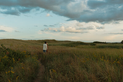 couple walks through field in pei