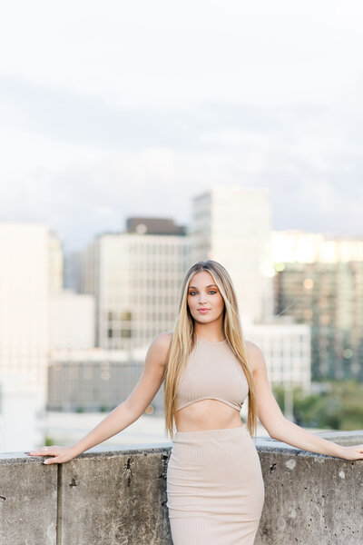 young woman posing on a rooftop with the city in the background