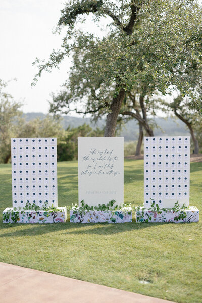 Modern wedding champagne wall and welcome signage installation with floral bases, designed by Eventive Designs for an outdoor Austin celebration.