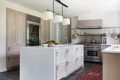 A Westwood kitchen design in Boston MA featuring light oak cabinets, a Wolf range, and a white tile backsplash in kitchen for a timeless and functional space.