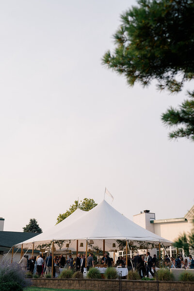 A NJ wedding reception under a sail cloth tent during sunset.