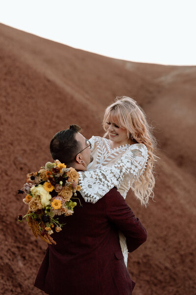 Bride being held up and swung around by groom at Painted Hills.