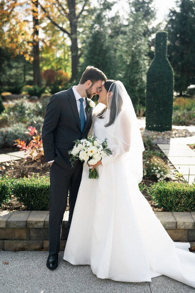 Timeless wedding portrait of bride and groom embracing in a fall garden with white bouquet, captured by Cleveland wedding photographer.