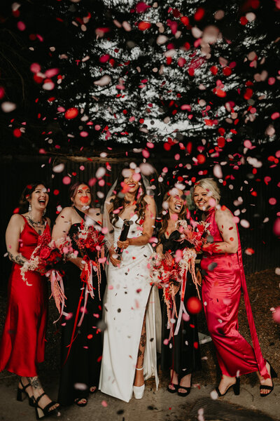 Bride and bridesmaids in pink dresses pop confetti cannons. 