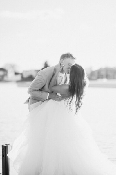 Bride and groom share a kiss on a dock after their wedding ceremony. Photo by Anna Brace, an Omaha NE Wedding Photographer