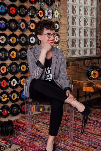 Event planner sitting on chair with legs crossed in front of vinyl record wall