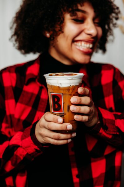 Girl laughing holding a Biggby Coffee drink.