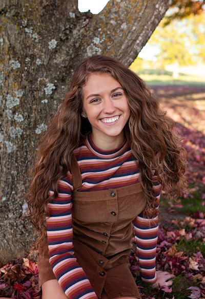 Senior picture of a girl with Fall leaves and flowing wavy hair