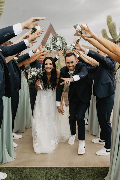 bride and groom duck under their bridal parties hands while smiling