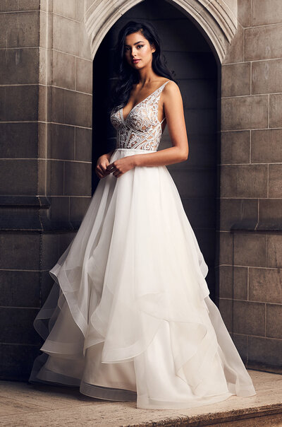 Paloma Blanca Style 4825 is a Silk Dupioni ball gown with numerous gorgeous details worked into the design. The bodice is adorned with sparkling beaded appliqués on the front and back, and there is box pleating on the skirt for all the regal feels. And no full skirt is complete without pockets!
