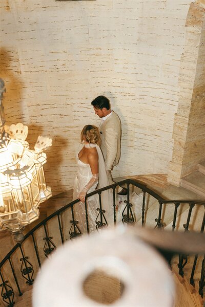 Bride and groom walking down the grand staircase at The Howey Mansion in Florida—timeless elegance at a historic luxury wedding venue, planned by Watters & Co. Events.