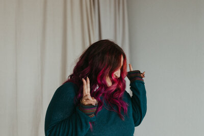 A person throwing up peace signs with both hands with their head turned away from the camera