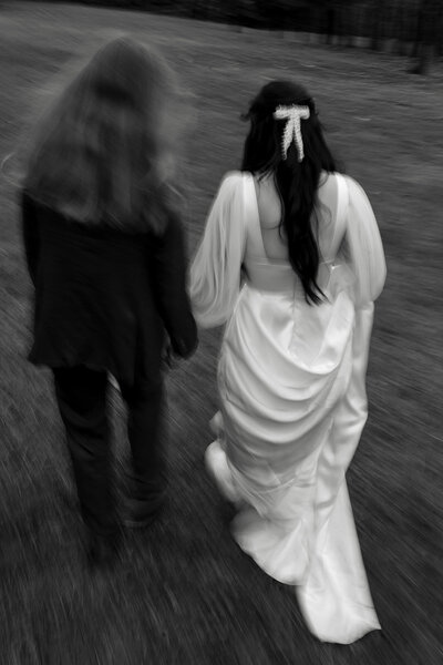 black and photo photo of a bride and groom walking away from the camera