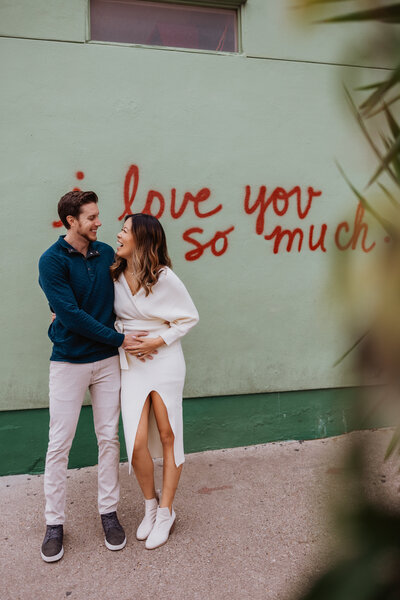 A couple poses in front of the "I Love You So Much" mural on South Congress during a family photo session