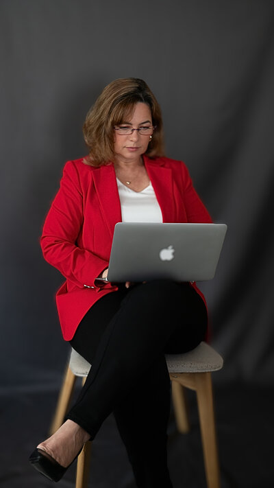 Brazilian woman sitting on a stool typing on her laptop