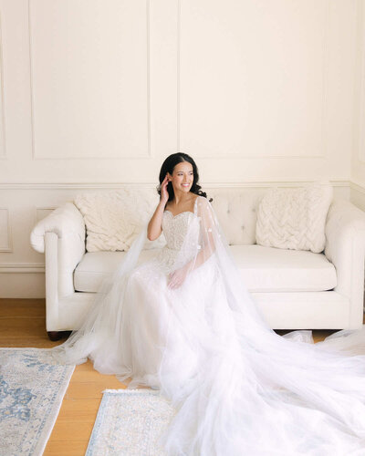 A bride posing for her wedding portrait sitting on a sofa.
