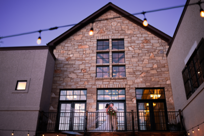 Nightime Blue sunset of Wedding Venue Silver Oaks Chateau located in Pacific Missouri with bride and groom standing on balcony with veil flying in background | Evalyn & Co. Photography