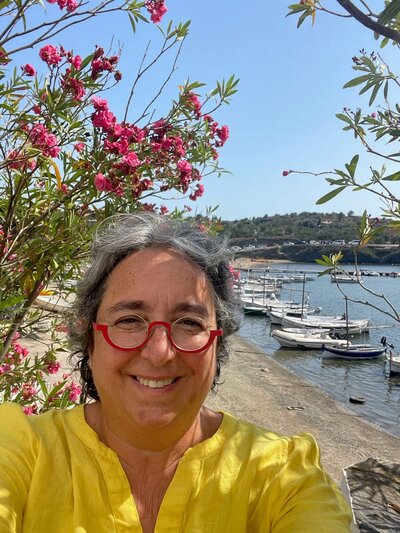Nadine Batya, member of the OPWF board, smiles in front of flowers. 