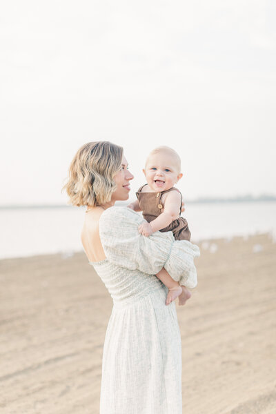 Mom holds her baby boy close while standing barefoot on the beach during a Kansas City 6 month milestone session.