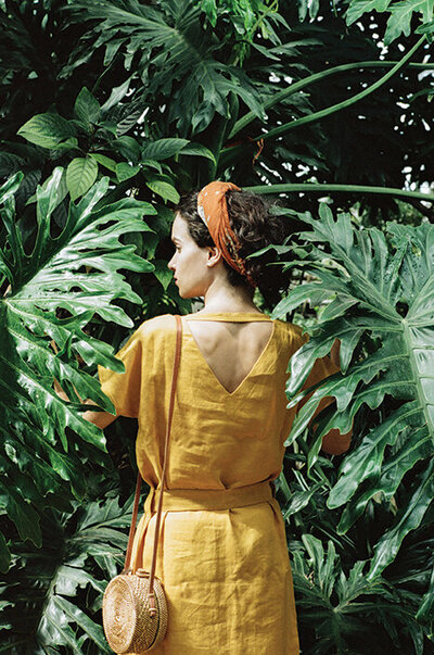 fashionable woman wearing a yellow dress amongst palm trees