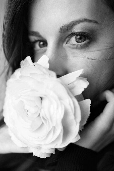 femme regardant l'objectif avec une grosse fleur devant la bouche