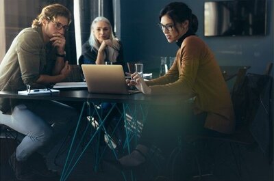 3 team members sitting a table viewing a laptop