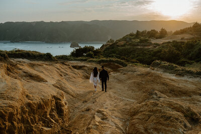 a wide landscape shot of R & J walking down through a valley  towards the cliffs overlooking the ocean