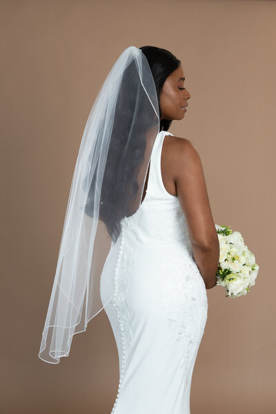 Bride wearing a fingertip veil with ribbon edge and holding a white and black bouquet