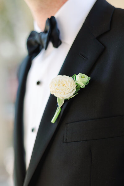 Close up of groom and his boutonniere on his wedding day tuxedo