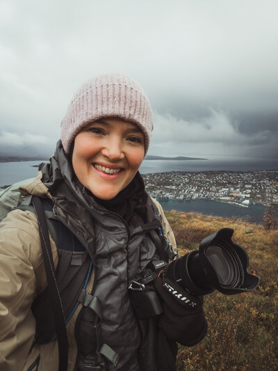 Elopement photographer smiling to teh camera on a mountain in Lofoten
