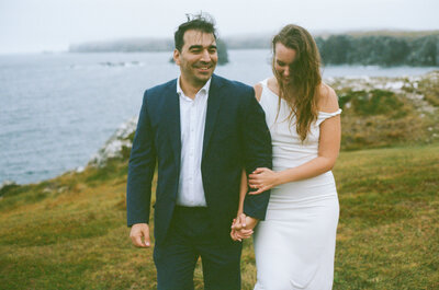 candid photo of bride and groom walking along the cliffs of Bonavista during elopement