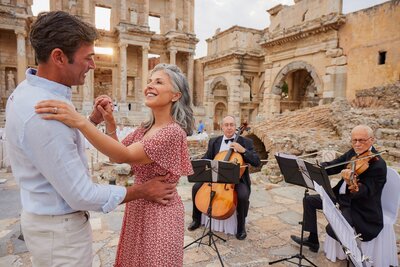 Couple dancing to live string music in front of ancient Roman ruins in Ephesus, Turkey — a romantic travel moment ideal for anniversaries and luxury group getaways