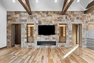 a stone fireplace wall with tv mount and wood beams
