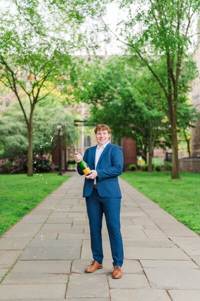 A Yale University student smiles on campus and pops Champagne. 