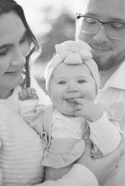 Black and white image of mom and dad holding baby with giggly smile looking at camera by Portland Family Photographer Emilie Phillipson Photography. 