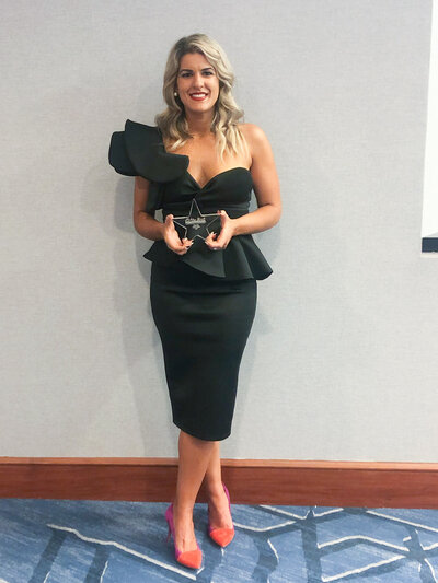 Woman in black dress and red shoes holding a star shaped award