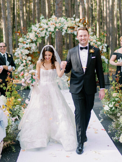 bride and groom holding hands and walking down the aisle designed by team of wedding planners in minneapolis minnesota