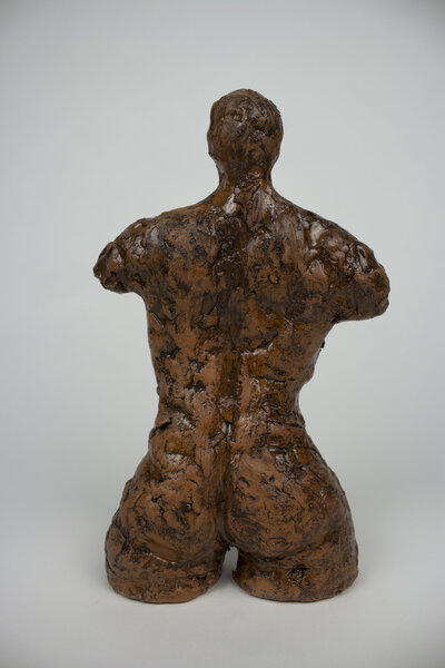 A ceramic bust of a feminine body with various cracks and brick textures