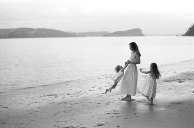 Seaside joy, held close. A soft black and white photography from a Sydney family photographer